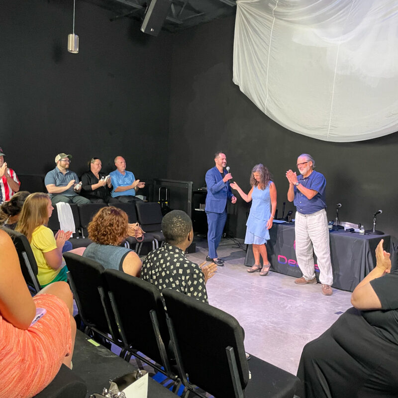 Michael speaking the front of an audience with other people